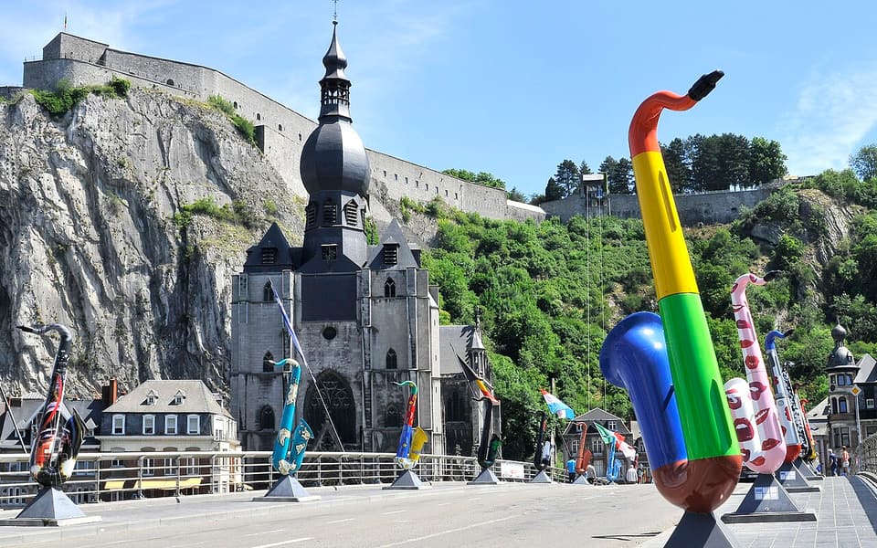 Saxophone sculptures on Dinant's Charles de Gaulle Bridge with the collegiate church and citadel behind
